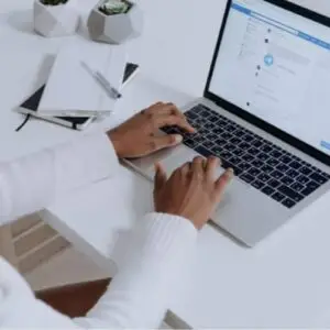 Woman typing on computer with Facebook showing on screen